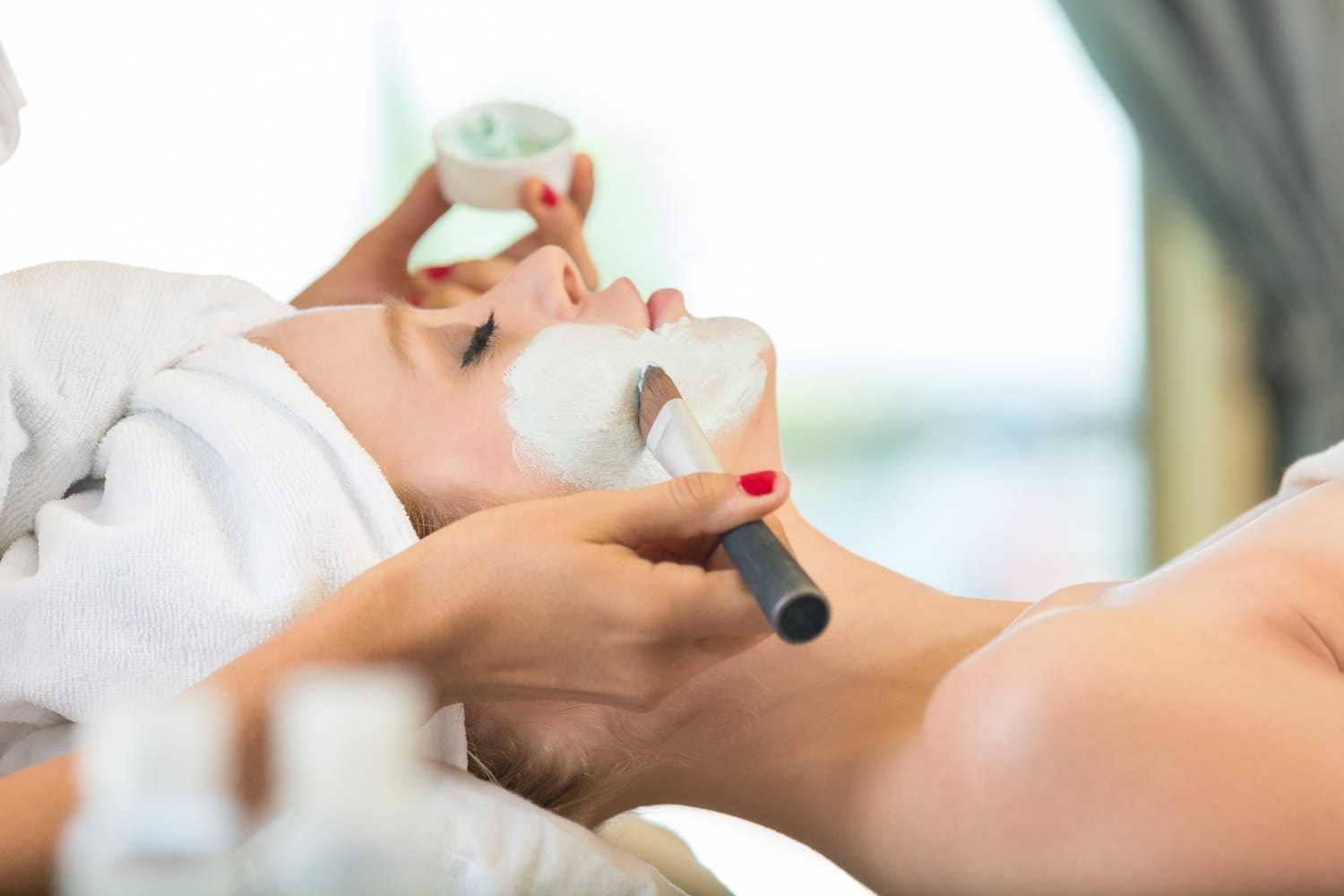 Woman receiving a facial mask treatment at a spa.