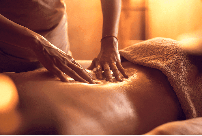 Person receiving a relaxing massage with oil in a warm, serene setting.